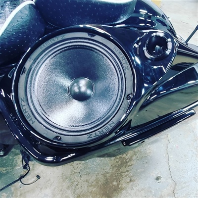 A close-up view of a large black speaker installed in the side panel of a motorcycle.