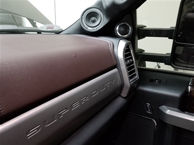 A close-up view of a car's interior showing the dashboard with "SUPER DUTY" embossed, two round speakers mounted on the A-pillar, and part of the passenger side door.