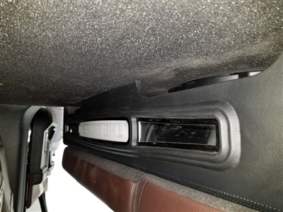 A close-up view of a car's interior showing a vent and speaker grille located under the dashboard.