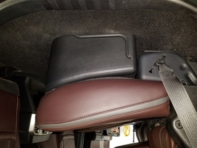 A close-up view of a car's interior showing a folded rear seat with a seatbelt, highlighting the space behind the seat and part of the vehicle's interior trim.