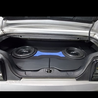 The trunk of a car with two large subwoofers installed in a custom enclosure, featuring a blue accent in the middle.