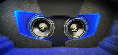 A close-up view of two large subwoofers installed in a custom enclosure with blue LED lighting accentuating the area around the speakers.