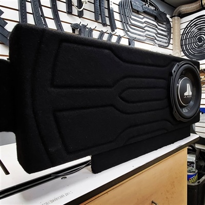 A custom black subwoofer enclosure with a JL Audio subwoofer installed, displayed in an automotive audio shop.
