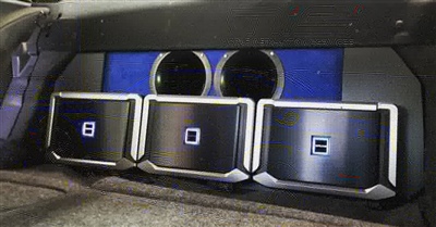 Close-up of a vehicle's interior showing three custom audio or control units with illuminated buttons labeled "8", "0", and "B", set in a panel with blue accents.
