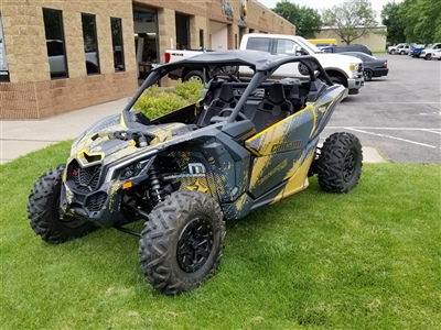 A rugged off-road vehicle with a black and yellow paint job parked on a grassy area outside a building.