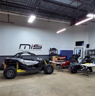 An indoor automotive shop featuring a black and yellow off-road vehicle, two motorcycles