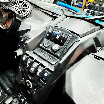 A close-up view of an off-road vehicle's dashboard featuring multiple control switches, buttons, and a digital display.