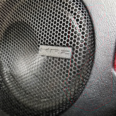 Close-up of a car speaker with a metal mesh grill, featuring a small badge labeled "JBL."