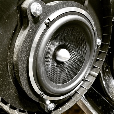Close-up of a car speaker with a metallic cone and surround, mounted in a black enclosure.
