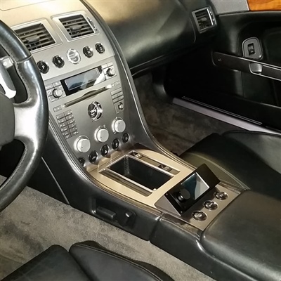 Interior of a luxury vehicle featuring a sleek center console with metallic accents, control knobs, and a small display screen. Black leather seats and a portion of the steering wheel are visible.