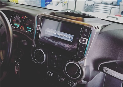 Close-up view of a car dashboard with a large touchscreen display and various control buttons, showing a garage in the background.