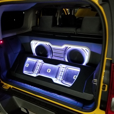  Rear view of a vehicle showcasing a custom audio system with illuminated speakers and amplifiers installed in the trunk.