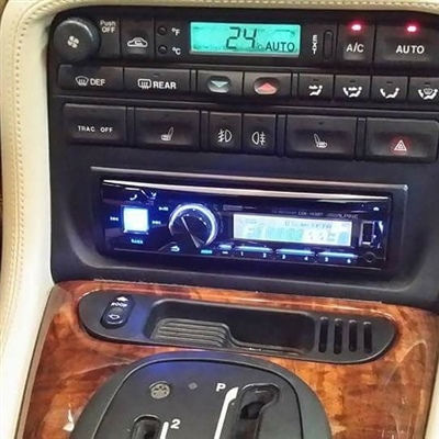 Close-up of a car's center console featuring climate control buttons, a digital display, and an aftermarket audio system installed below.