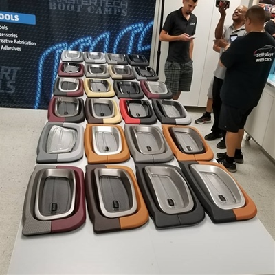 A display table showcasing various car gear shifters in different colors and styles, with people standing and talking in the background.