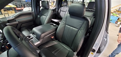 Interior of a vehicle with black leather seats, showing the front row and part of the back row, with the driver and passenger doors open.