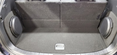 Close-up of an empty car trunk with two integrated subwoofers on the sides.