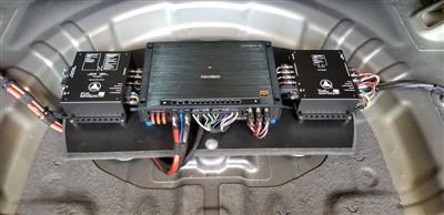 Interior of a vehicle's trunk with exposed battery and wiring components, showcasing the vehicle's electrical setup.