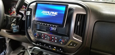 Close-up of a car dashboard featuring an Alpine touchscreen display, control buttons, and air vents.