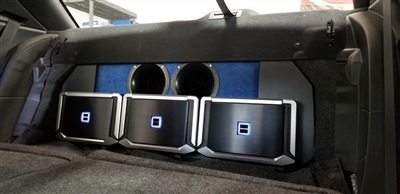 Close-up view of a custom audio system installed in a vehicle's trunk, featuring multiple amplifiers and speakers.