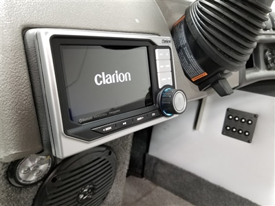 Close-up of a Clarion audio system installed in a vehicle, with surrounding components and a speaker visible.