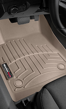 A beige car floor mat with ridged patterns is placed under the driver's side pedals.