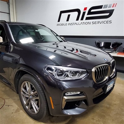 Dark grey BMW SUV parked inside a garage with "Mobile Installation Services" signage on the wall in the background.