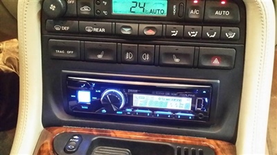 A close-up view of a car's center console displaying the radio, climate control buttons, and a digital display screen.