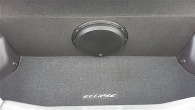 The interior of a car trunk showing a black subwoofer installed in the back panel, with a carpeted floor bearing the "Eclipse" logo.